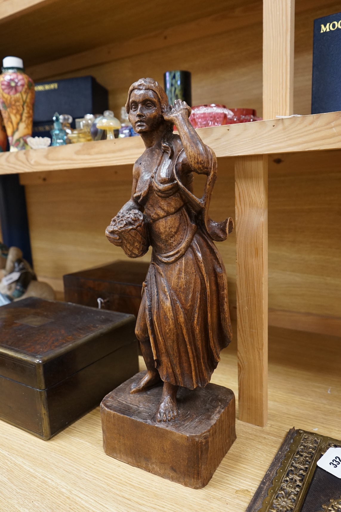 A carved walnut figure of a girl holding a basket of flowers, 54cm high